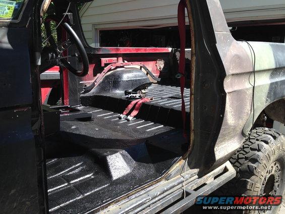1979 Ford Bronco interior showing removed seats, black bedliner, and red seatbelts