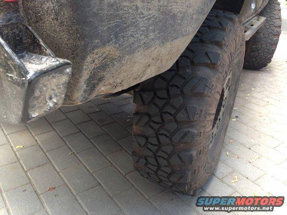 Rear bumper and large off-road tire of a vehicle on a paved surface