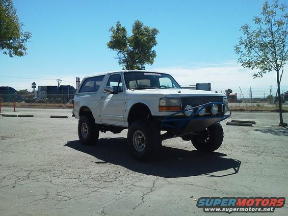 White 1994 Ford Bronco with custom blue bumper and off-road tires