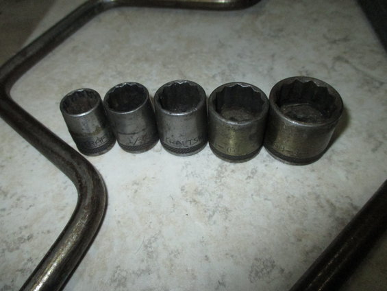 Socket wrench set with five sockets and two handles on a tiled surface