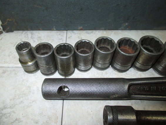Socket wrench set with multiple sockets and a ratchet handle, some sockets show wear