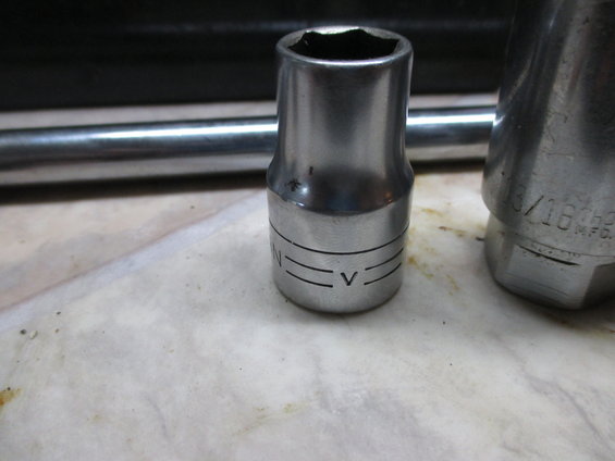 Close-up of two metal sockets and a metal bar on a textured surface