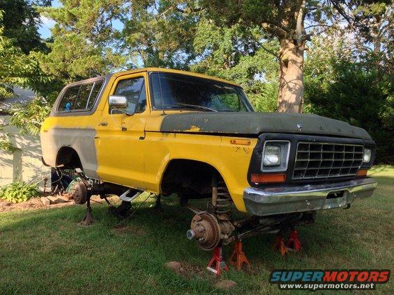 Yellow and gray 1979 Ford Bronco on jack stands with front end disassembled