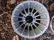 1979 Ford Bronco - A single alloy wheel is shown lying on the ground amidst fallen leaves.