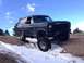 1983 Ford Bronco - A black Ford Bronco navigates a snowy, off-road trail under a partly cloudy sky.