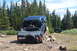 1983 Ford Bronco - A dark blue 1983 Ford Bronco navigates a rocky obstacle on an off-road trail, with another vehicle visible in the background.