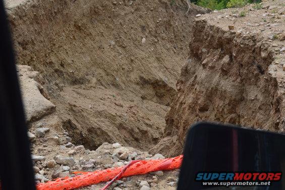 View of a large dirt embankment collapse with orange safety netting in the foreground