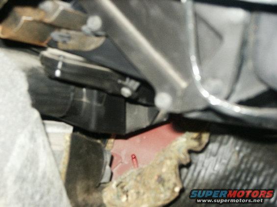Undercarriage view of vehicle parts, including red painted metal and black plastic components