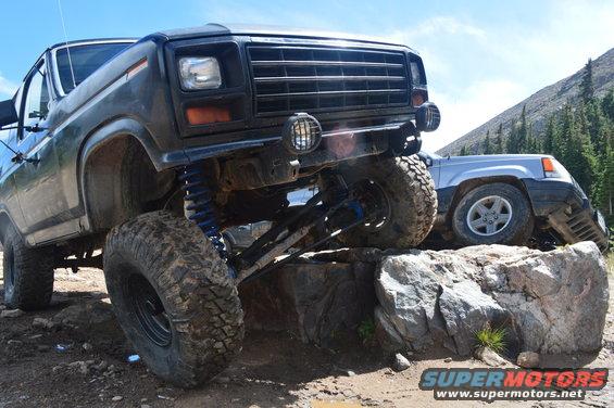 Dark green Ford Bronco with lifted suspension on rocks, front grille visible
