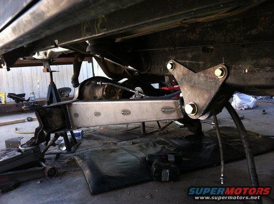 Underbody of vehicle with suspension and a metal fuel tank, Supermotors.net logo visible