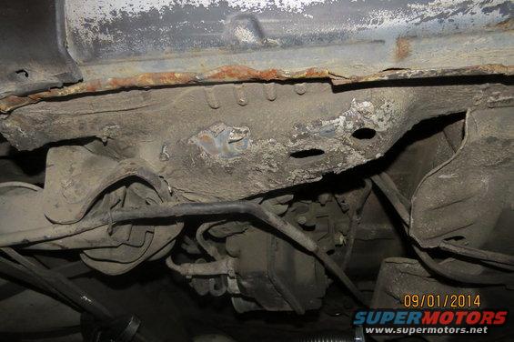 rusted frame and suspension components under a car