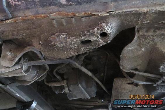Undercarriage of a rusty car with visible suspension components and exhaust system