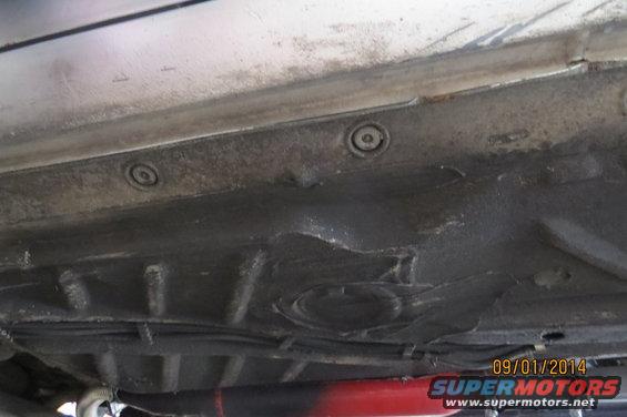Underside view of a car with visible rust and undercoating