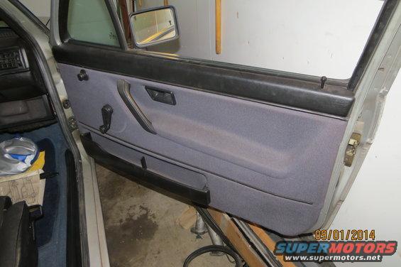 Interior door panel of a car, gray fabric with black trim. Date stamp visible