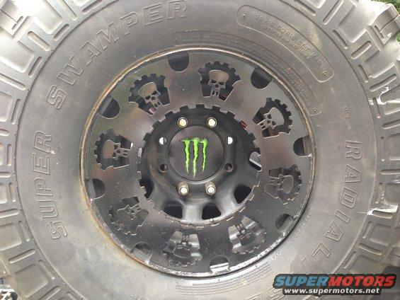 Custom wheel with skull and gear cutouts and Monster Energy logo on a Super Swamper tire