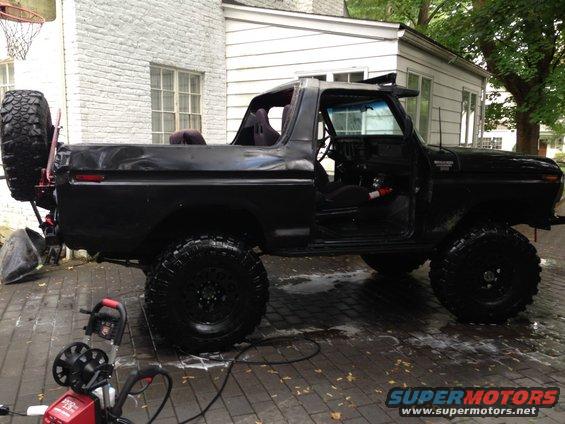 Black 1970s Ford Bronco, 3/4 front view, with spare tire mounted on the rear