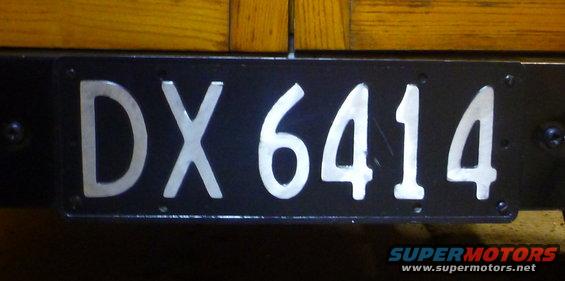 Black license plate with silver characters DX 6414