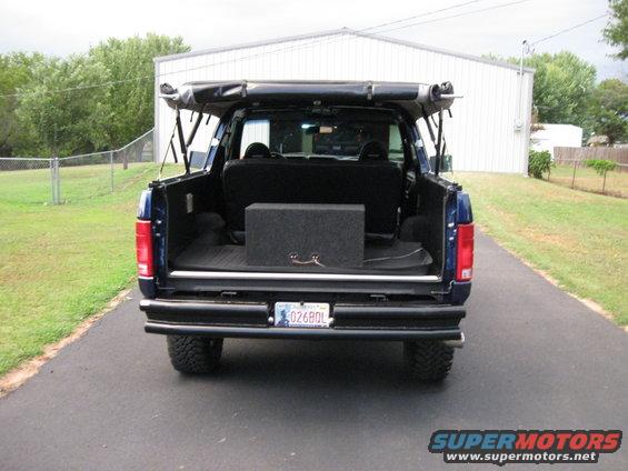 Blue Ford Bronco rear view with soft top deployed, aftermarket bumper, and subwoofer box inside