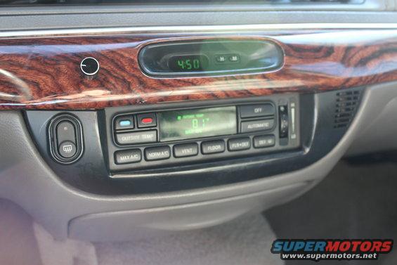 Car interior showing climate controls, clock, and wood trim