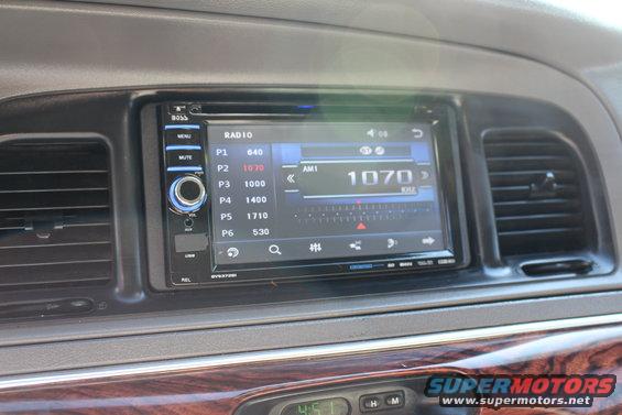 Dashboard with touchscreen radio and wood trim. Radio shows AM 1070