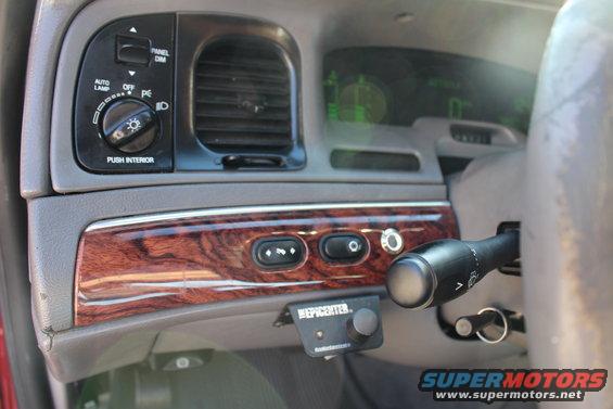 Dashboard interior of a 2002 Mercury Grand Marquis showing wood trim, air vents, headlight controls, and a steering column