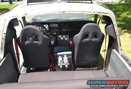 Interior view of a truck with racing seats, a fire extinguisher, and a cooler with water bottles