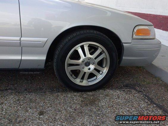 Silver sedan's front passenger side wheel and fender. The car has a chrome trim strip along the lower door