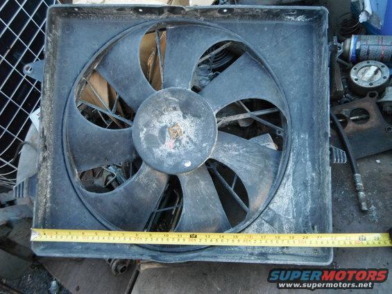 Radiator fan with a tape measure across it. Some tools and cans are in the background