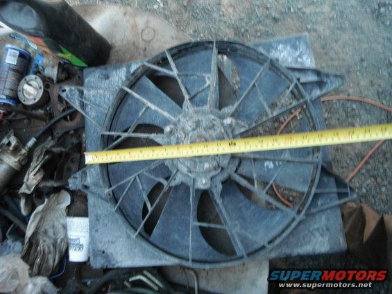 Radiator fan assembly with a yellow measuring tape across it