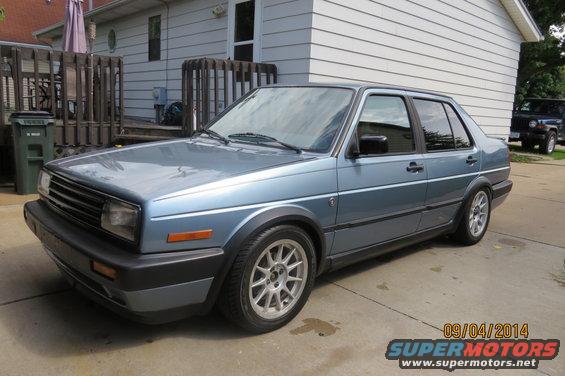 1990 Volkswagen Jetta sedan, light blue, parked in driveway next to a dark SUV