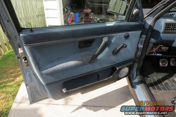 Car's blue fabric door panel with crank window, handle, and speaker
