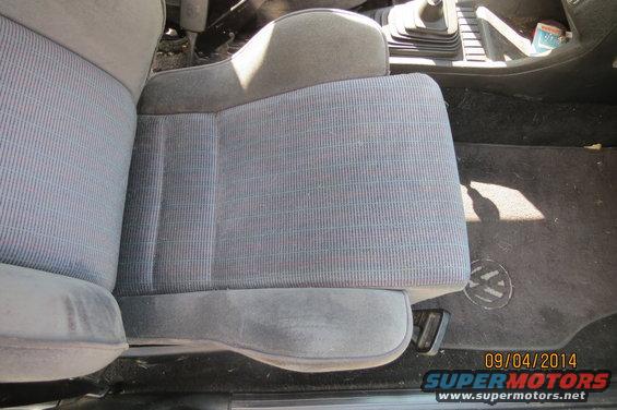 Volkswagen interior showing patterned fabric seats and a floor mat with a VW logo