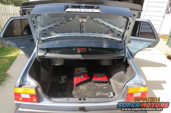 1990 Volkswagen Jetta trunk open, showing two red bags and spare tire well