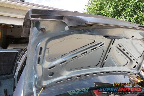 inside of a car trunk lid, another car visible in garage