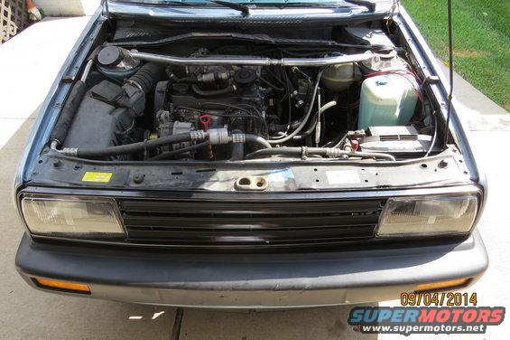 Blue 1990 Volkswagen Jetta engine bay with visible engine components and battery