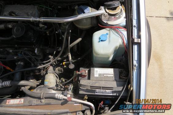 1990 Volkswagen Jetta engine bay with battery, coolant reservoir, and strut bar