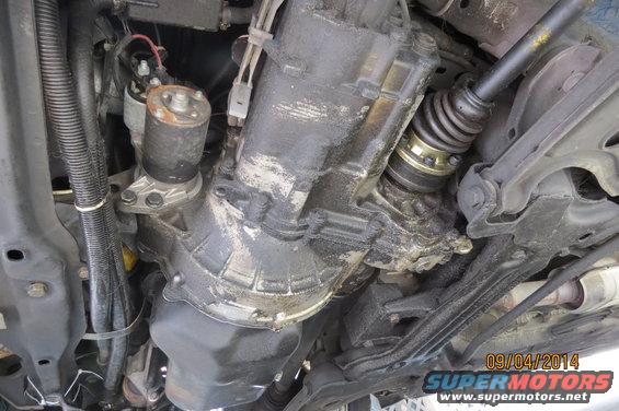 Underside of a vehicle showing a greasy transmission, starter motor, and CV axle