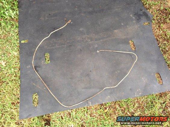 Metal brake line on black mat with grass background. Supermotors.net logo visible