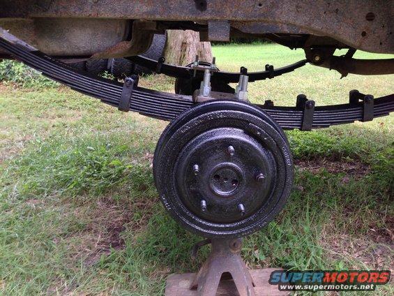 close-up of vehicle's rear axle, drum brake, and leaf springs supported by jack stands
