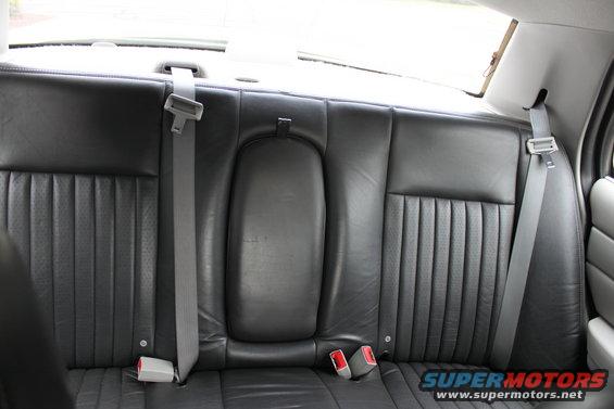 Back seat with black leather upholstery and seatbelts