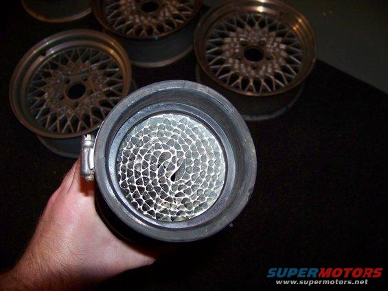 Air filter with honeycomb interior, held by a hand, with mesh wheels in background