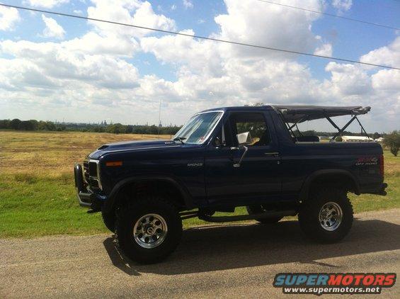 Dark blue 1982 Ford Bronco side view with soft top and off-road tires