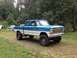 1971 Ford F-250 - A lifted pickup truck with a two-tone paint scheme sits in a wooded area.