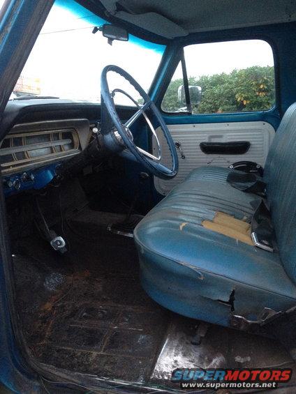 Blue truck interior with torn seat, cracked dashboard, and steering wheel