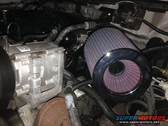 Engine bay with a large purple cone air filter and AC compressor