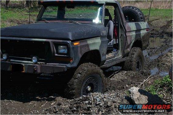 Camouflaged Ford Bronco stuck in mud, front 3/4 view