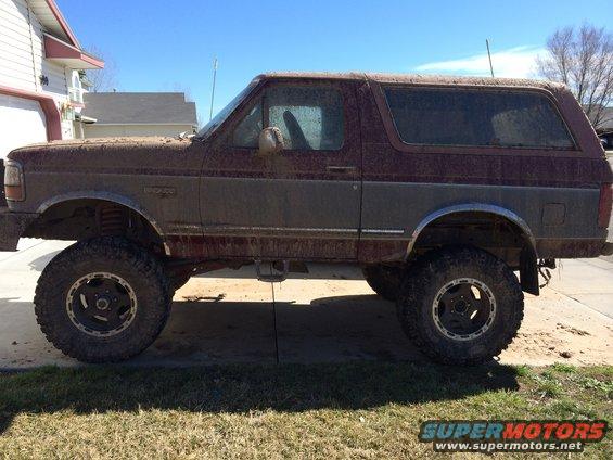 Side view of a muddy 1993 Ford Bronco with lifted suspension and off-road tires