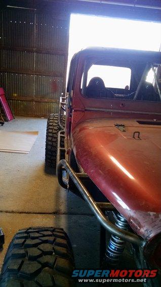 Red buggy with roll cage and large off-road tires inside a garage