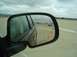 2004 Cadillac CTS - View from the side mirror of a vehicle on a track, with cones marking a course and another car in the distance.