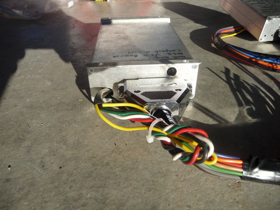 Aluminum electronic control unit with "MS2 V.2.0 Board" handwritten text and a DB9 connector with a colorful wire harness